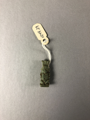  <em>Amulet in the Form of Bes</em>. Faience, 15/16 × 3/8 × 1/4 in. (2.4 × 1 × 0.7 cm). Brooklyn Museum, Brooklyn Museum Collection, X249.29. Creative Commons-BY (Photo: , CUR.X249.29_view01.jpg)