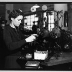 [Untitled]  (Young Woman Standing at Tabletop Thread Machine)
