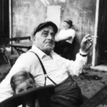 Old Man with Suspenders Smoking + Girl Behind Chair, Italy